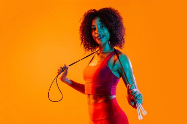 Sportif siyahi kadın spor kıyafetleri giyiyor spor salonunda, renkli dramatik ışıklandırma - spor yapan Afro-Amerikan bayan sporcu