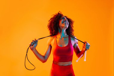 Sportif siyahi kadın spor kıyafetleri giyiyor spor salonunda, renkli dramatik ışıklandırma - spor yapan Afro-Amerikan bayan sporcu