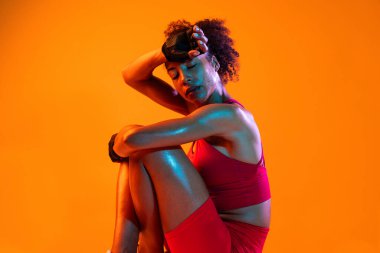 Sportif siyahi kadın spor kıyafetleri giyiyor spor salonunda, renkli dramatik ışıklandırma - spor yapan Afro-Amerikan bayan sporcu