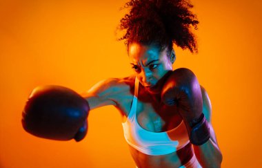 Sportif siyahi kadın spor kıyafetleri giyiyor spor salonunda, renkli dramatik ışıklandırma - spor yapan Afro-Amerikan bayan sporcu