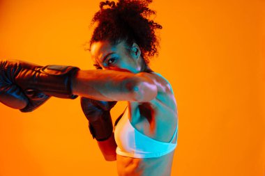 Sportif siyahi kadın spor kıyafetleri giyiyor spor salonunda, renkli dramatik ışıklandırma - spor yapan Afro-Amerikan bayan sporcu