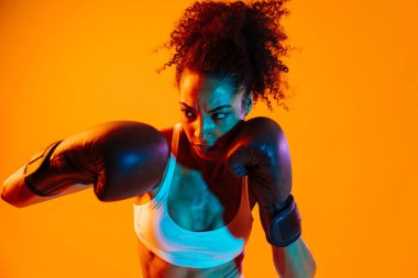 Sportif siyahi kadın spor kıyafetleri giyiyor spor salonunda, renkli dramatik ışıklandırma - spor yapan Afro-Amerikan bayan sporcu