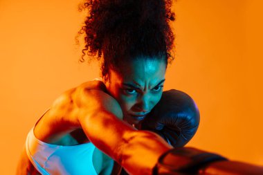 Sportif siyahi kadın spor kıyafetleri giyiyor spor salonunda, renkli dramatik ışıklandırma - spor yapan Afro-Amerikan bayan sporcu