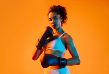 Sportif siyahi kadın spor kıyafetleri giyiyor spor salonunda, renkli dramatik ışıklandırma - spor yapan Afro-Amerikan bayan sporcu