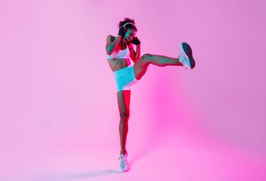 Sportif siyahi kadın spor kıyafetleri giyiyor spor salonunda, renkli dramatik ışıklandırma - spor yapan Afro-Amerikan bayan sporcu