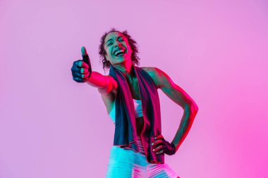 Sportif siyahi kadın spor kıyafetleri giyiyor spor salonunda, renkli dramatik ışıklandırma - spor yapan Afro-Amerikan bayan sporcu