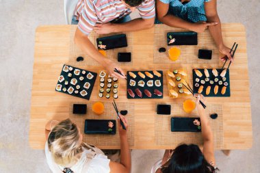 Çok ırklı bir grup genç arkadaş evde buluşup suşi yiyorlar. Çok ırklı mutlu insanlar öğle yemeği yerken kaynaşıyorlar.