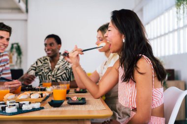 Çok ırklı bir grup genç arkadaş evde buluşup suşi yiyorlar. Çok ırklı mutlu insanlar öğle yemeği yerken kaynaşıyorlar.