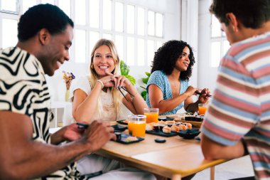 Çok ırklı bir grup genç arkadaş evde buluşup suşi yiyorlar. Çok ırklı mutlu insanlar öğle yemeği yerken kaynaşıyorlar.