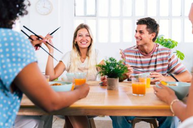 Çok ırklı bir grup genç arkadaş evde buluşuyor ve yemek yerken çok ırklı ve mutlu insanlar yemek yiyor.