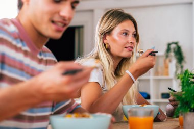 Çok ırklı bir grup genç arkadaş evde buluşuyor ve yemek yerken çok ırklı ve mutlu insanlar yemek yiyor.