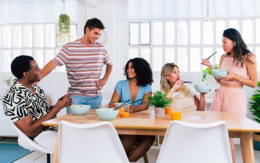 Çok ırklı bir grup genç arkadaş evde buluşuyor ve yemek yerken çok ırklı ve mutlu insanlar yemek yiyor.