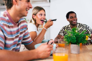 Çok ırklı bir grup genç arkadaş evde buluşuyor ve yemek yerken çok ırklı ve mutlu insanlar yemek yiyor.
