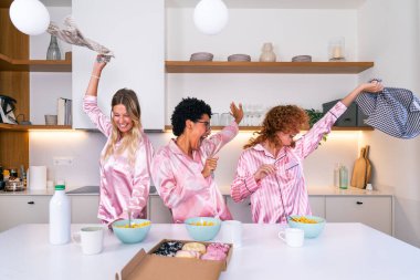 Evde pijama partisi sırasında kahvaltı eden çok ırklı bir grup genç kız arkadaş mutlu mutlu en iyi arkadaşlar kaynaşıyor ve evde eğleniyorlar.