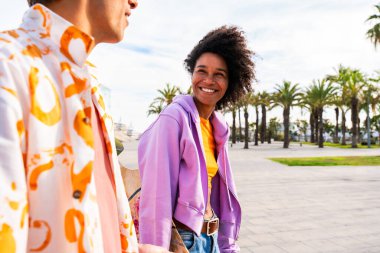 Açık havada kaykay yapan çok ırklı genç bir çift - iki arkadaş şehir bölgelerinde kayak yaparken eğleniyor, gençlik, çeşitlilik, yeşil traksiyonlar ve hareketlilik kavramları