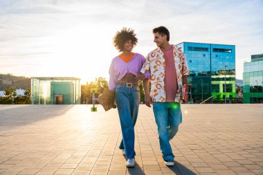 Açık havada kaykay yapan çok ırklı genç bir çift - iki arkadaş şehir bölgelerinde kayak yaparken eğleniyor, gençlik, çeşitlilik, yeşil traksiyonlar ve hareketlilik kavramları