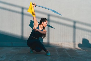 Çinli genç bir kadın dışarıda Wushu kung fu 'su yapıyor. Dövüş sanatları eğitimi alan genç bir kız..