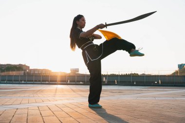 Çinli genç bir kadın dışarıda Wushu kung fu 'su yapıyor. Dövüş sanatları eğitimi alan genç bir kız..