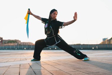 Çinli genç bir kadın dışarıda Wushu kung fu 'su yapıyor. Dövüş sanatları eğitimi alan genç bir kız..