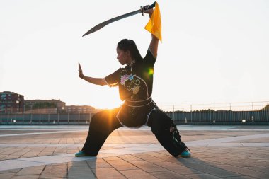 Çinli genç bir kadın dışarıda Wushu kung fu 'su yapıyor. Dövüş sanatları eğitimi alan genç bir kız..