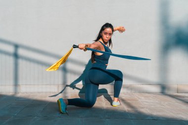 Çinli genç bir kadın dışarıda Wushu kung fu 'su yapıyor. Dövüş sanatları eğitimi alan genç bir kız..