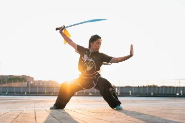 Çinli genç bir kadın dışarıda Wushu kung fu 'su yapıyor. Dövüş sanatları eğitimi alan genç bir kız..