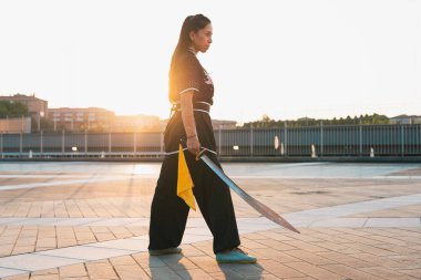 Çinli genç bir kadın dışarıda Wushu kung fu 'su yapıyor. Dövüş sanatları eğitimi alan genç bir kız..