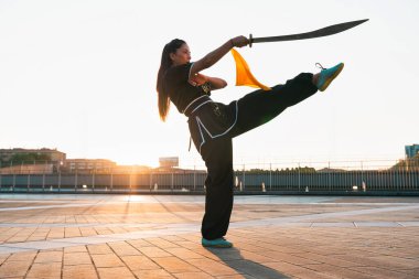 Çinli genç bir kadın dışarıda Wushu kung fu 'su yapıyor. Dövüş sanatları eğitimi alan genç bir kız..