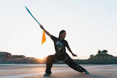 Çinli genç bir kadın dışarıda Wushu kung fu 'su yapıyor. Dövüş sanatları eğitimi alan genç bir kız..