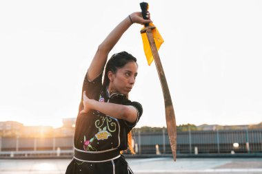 Çinli genç bir kadın dışarıda Wushu kung fu 'su yapıyor. Dövüş sanatları eğitimi alan genç bir kız..