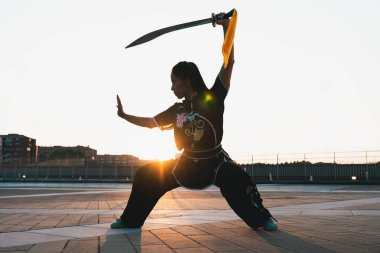 Çinli genç bir kadın dışarıda Wushu kung fu 'su yapıyor. Dövüş sanatları eğitimi alan genç bir kız..