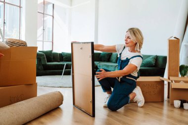 Bekar bir kadın yeni bir daireye taşınıyor. Orta yaşlı, son sınıf güzel bir kadın yeni evde kutuları falan taşıyor. Yaşam tarzı ve gayrimenkul kavramı.