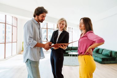 Emlakçı yeni bir daire gösteriyor ve genç bir çifte iyi bir yatırım yapıyor. Kadın ve erkek, şehrin zengin bir bölgesinde mülk satın alıyorlar. Sözleşmeyi imzalıyorum..