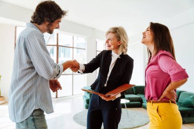 Emlakçı yeni bir daire gösteriyor ve genç bir çifte iyi bir yatırım yapıyor. Kadın ve erkek, şehrin zengin bir bölgesinde mülk satın alıyorlar. Sözleşmeyi imzalıyorum..