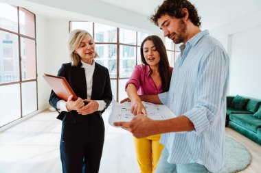 Emlakçı yeni bir daire gösteriyor ve genç bir çifte iyi bir yatırım yapıyor. Kadın ve erkek şehrin zengin bir bölgesinde mülk satın alıyorlar..