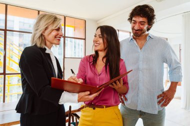 Emlakçı yeni bir daire gösteriyor ve genç bir çifte iyi bir yatırım yapıyor. Kadın ve erkek, şehrin zengin bir bölgesinde mülk satın alıyorlar. Sözleşmeyi imzalıyorum..