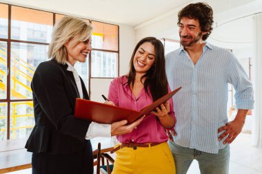 Emlakçı yeni bir daire gösteriyor ve genç bir çifte iyi bir yatırım yapıyor. Kadın ve erkek, şehrin zengin bir bölgesinde mülk satın alıyorlar. Sözleşmeyi imzalıyorum..