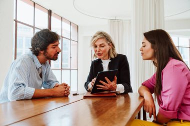 Emlakçı yeni bir daire gösteriyor ve genç bir çifte iyi bir yatırım yapıyor. Kadın ve erkek, şehrin zengin bir bölgesinde mülk satın alıyorlar. Sözleşmeyi imzalıyorum..