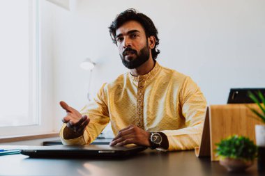 Ofisteki Pakistanlı iş adamı. Geleneksel kıyafetleri olan genç bir iş adamı ofisinde çalışıyor..