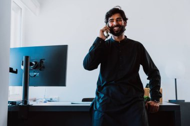 Ofisteki Pakistanlı iş adamı. Geleneksel kıyafetleri olan genç bir iş adamı ofisinde çalışıyor..
