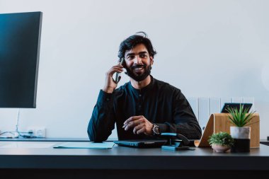 Ofisteki Pakistanlı iş adamı. Geleneksel kıyafetleri olan genç bir iş adamı ofisinde çalışıyor..