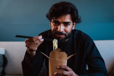 Geleneksel kıyafeti olan Pakistanlı adam erişte yiyor..