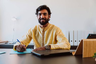 Ofisteki Pakistanlı iş adamı. Geleneksel kıyafetleri olan genç bir iş adamı ofisinde çalışıyor..