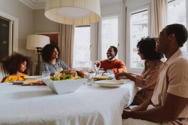 Tatillerde öğle yemeği için aile evinde bir araya gelen bir aile görüntüsü. Aile üyeleri evde güzel yemekler yiyip, sevgi ve olumlu duyguları paylaşıyorlar..