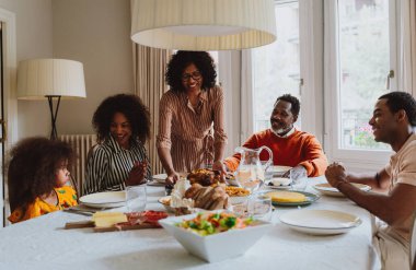 Tatillerde öğle yemeği için aile evinde bir araya gelen bir aile görüntüsü. Aile üyeleri evde güzel yemekler yiyip, sevgi ve olumlu duyguları paylaşıyorlar..