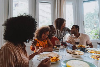 Tatillerde öğle yemeği için aile evinde bir araya gelen bir aile görüntüsü. Aile üyeleri evde güzel yemekler yiyip, sevgi ve olumlu duyguları paylaşıyorlar..