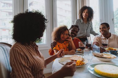 Tatillerde öğle yemeği için aile evinde bir araya gelen bir aile görüntüsü. Aile üyeleri evde güzel yemekler yiyip, sevgi ve olumlu duyguları paylaşıyorlar..