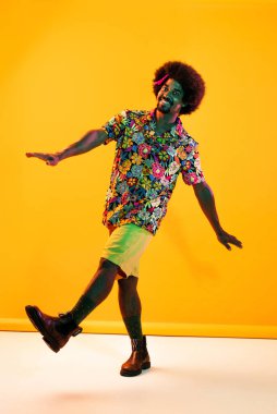 Renkli arka planda Afrikalı adam portresi - şık giyinen havalı siyah erkek, yaratıcı renkli ışıklandırma