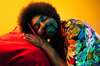 Renkli arka planda Afrikalı adam portresi - şık giyinen havalı siyah erkek, yaratıcı renkli ışıklandırma