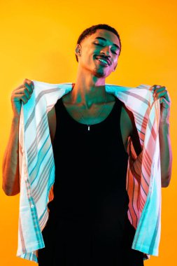 Renkli arka planda Afrikalı genç adam portresi - şık giyinen havalı siyah erkek, yaratıcı renkli ışıklandırma